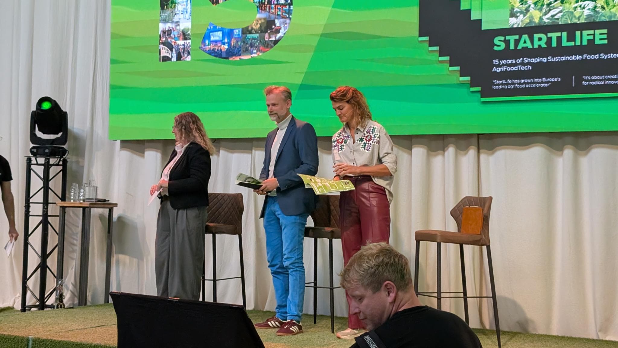 Startlife CEO Dr. Nikki Harrison, Sebastiaan Berendse, Director Value Creation & Impact at WUR, and Marjolein Brasz, CEO of Foodvalley, after receiving the first Startlife 15 magazine on stage